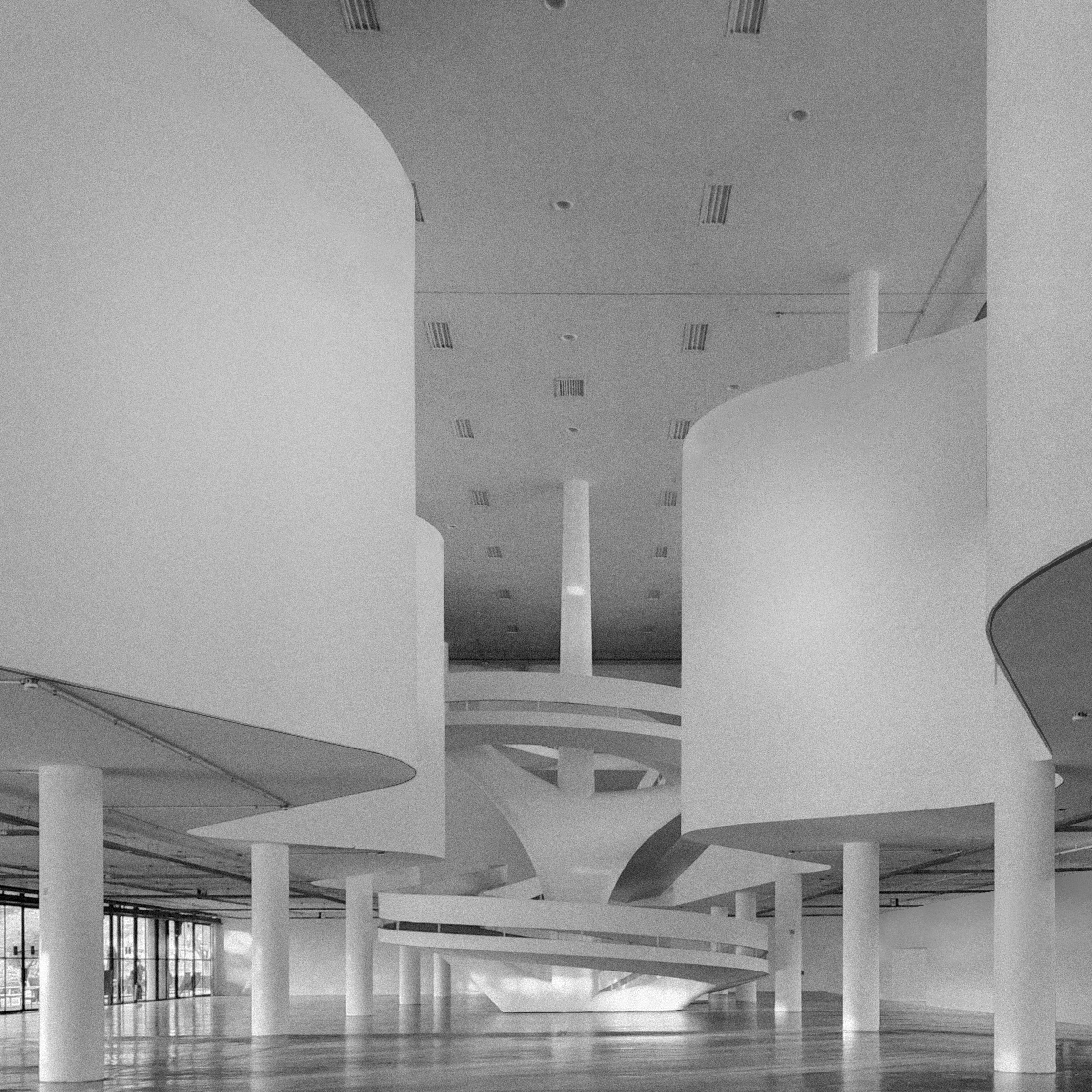 Image of the central opening of the Bienal Pavilion in black and white without people and with a wall that connects the second to the third floor
